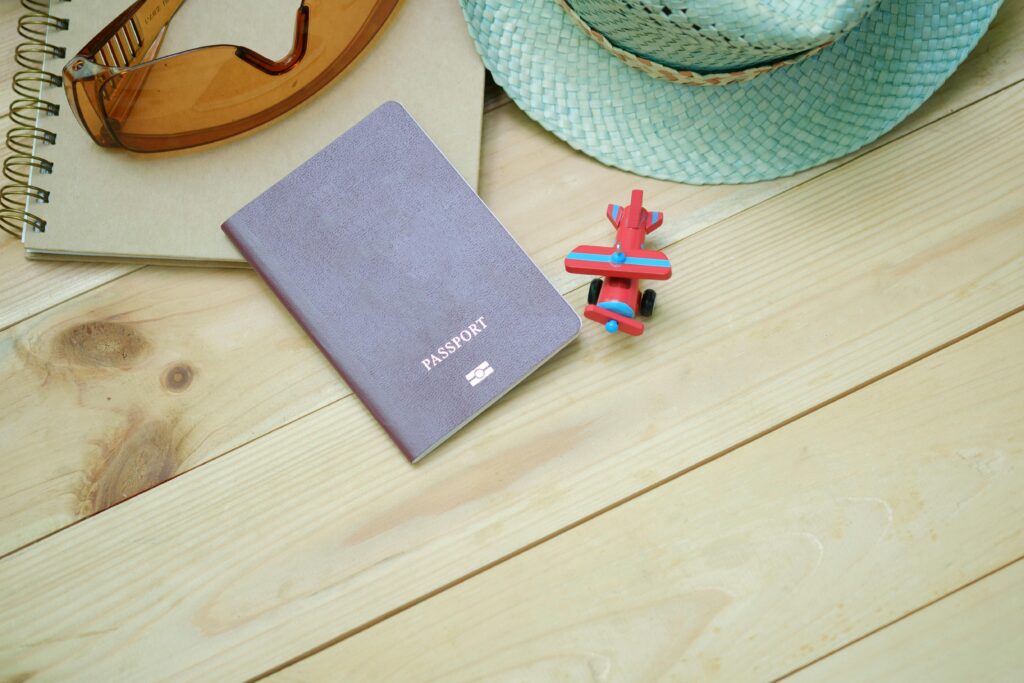 How to Renew Your Lebanese Passport in Halifax Flat lay of travel essentials including passport, notebook, toy airplane, sunglasses, and straw hat.