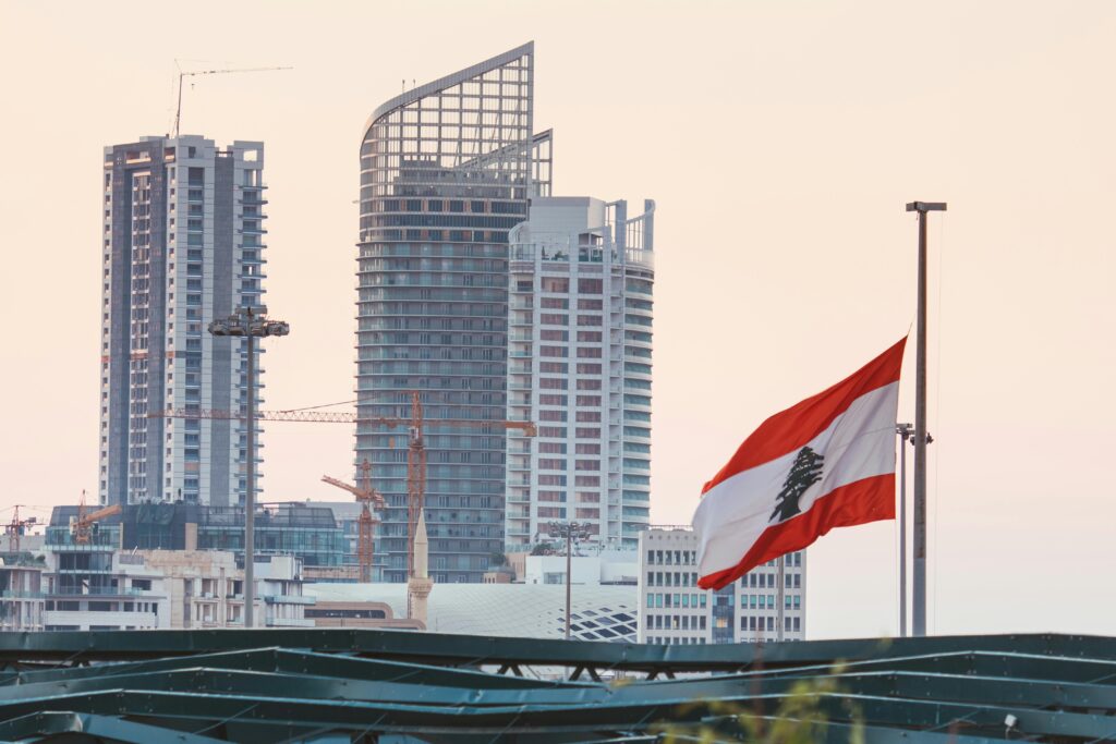 Urban skyline of Beirut with a prominent Lebanese flag gently waving at sunset.